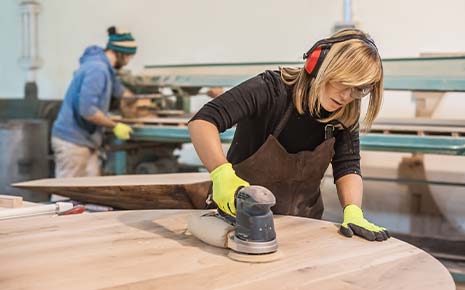 female carpenter sanding table