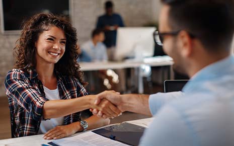 woman being hired and shaking hand of employer